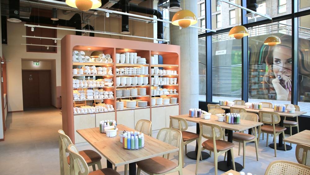 Interior of BonBon Pottery in Wembley Park with shelves of ceramic pieces and painting tables