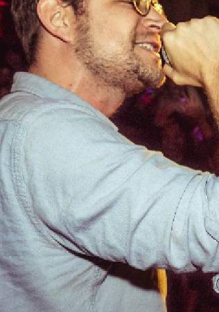 Someone performing with a microphone and can see audience in the background.