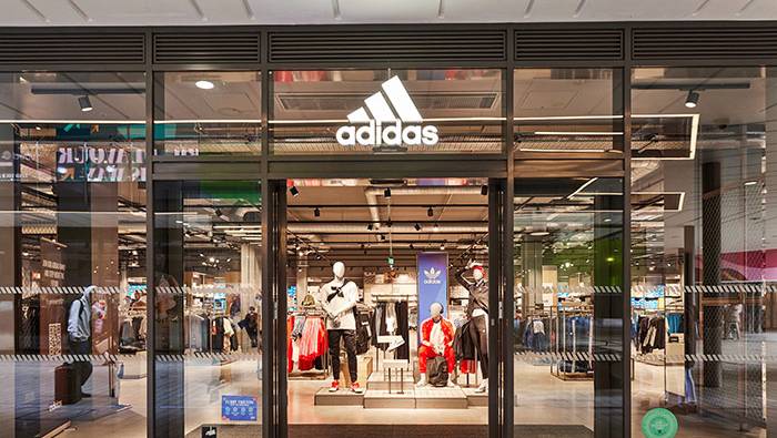 Exterior shopfront of an adidas store with the brand logo above a glass facade
