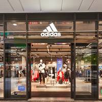 Exterior shopfront of an adidas store with the brand logo above a glass facade