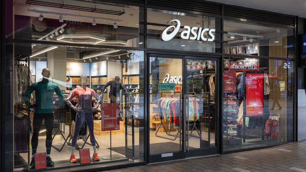 ASICS storefront with illuminated signage at London Designer Outlet, Wembley Park