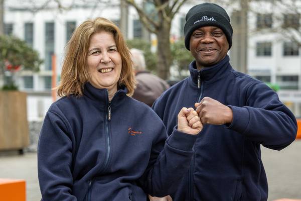 Carla Martins, head of Wembley Park's cleaning team, and supervisor William Kobenan smiling and bumping fists, both wearing navy Wembley Park fleeces