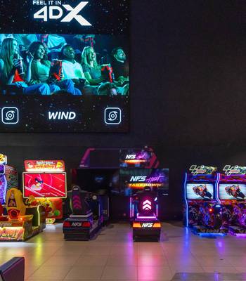 A Feel It in 4DX display above a row of racing and arcade games at Cineworld Wembley