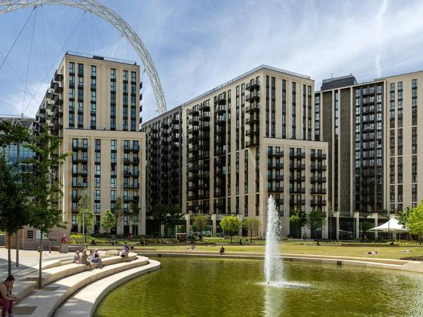 Residents using public green space in Union Park at Wembley Park, north west London, with modern apartments and Wembley Stadium in the background