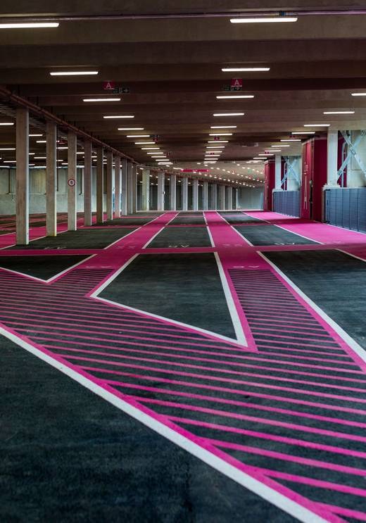 Interior view of Pink Parking at Wembley Park showing spacious parking bays with distinctive pink and black diagonal striped road markings, white bord