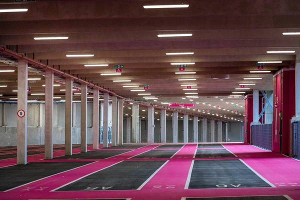 Interior of Pink Parking at Wembley Park showing Zone A and Zone B wayfinding signage, fire exit signs, speed limit sign, rows of spacious parking bay